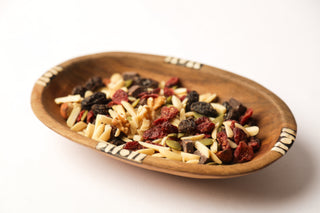 Oval bowl full of different nuts and dried fruits